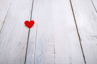 Aşkı basit ve derin bir düşünceyle ifade etmek için beyaz tahta bir arka planda küçük kırmızı kağıt bir kalp..