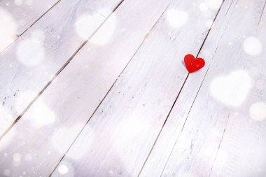Beyaz ahşap arka planda bokeh etkisi olan küçük kırmızı bir kalp. Aşkı basit ve derin bir düşünceyle ifade etmek için. 