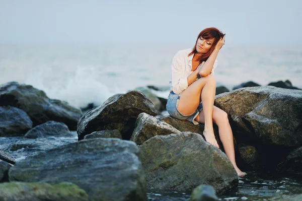 A menina solitária em pedras do mar — Fotografia de Stock
