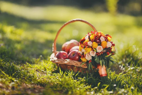Renkli elma ve güzel çiçekler ile çim üzerinde duran sepeti 