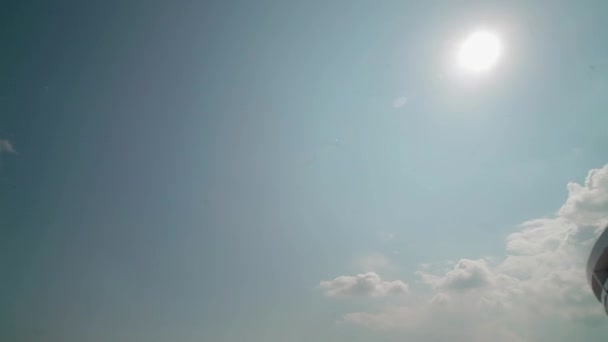 El edificio moderno y el cielo azul con un sol brillante y nubes blancas — Vídeo de stock