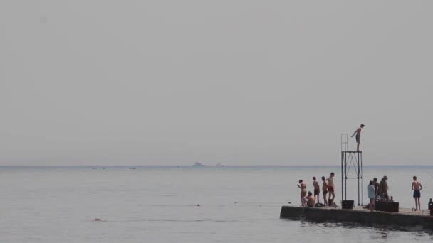 Люди плавают и прыгают в воду — стоковое видео