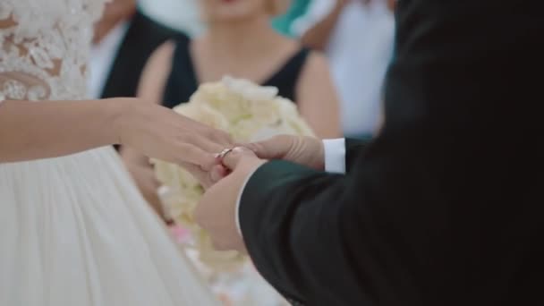 The groom dresses a ring to the bride under a wedding arch at a ceremony — Stock Video
