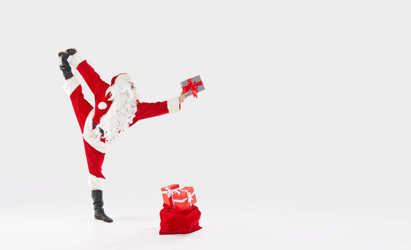 Joyful Santa Claus jumps high and dances with happiness with gifts on a white background. Concept for Christmas and New Year holidays and sales. Banner