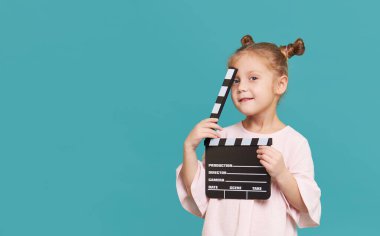 Funny smiling child girl hold film making clapperboard isolated on blue background. Little clipmaker, acting training. Funny face. Copy space for text.	