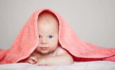 Beyaz arka planda beyaz havlu giymiş şirin bir çocuğun yakın plan portresi. Banyo yapan bebekler ve huzurlu bir uyku. Komik çocuk yüzü