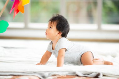 Mutlu küçük bebek emeklemeye ve renkli plastik rüzgar türbinine bakmaya başladı. Bebek Faaliyetleri Geliştirme Konsepti.