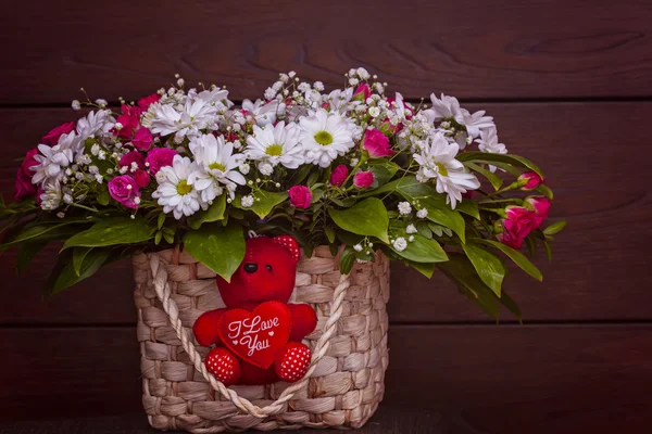 Ein roter reizender Bär als Geschenk mit Blumen im Korb — Stockfoto