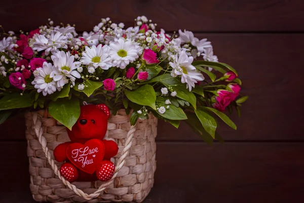 Bascket çiçeklerle bir hediye olarak bir kırmızı sevimli ayı