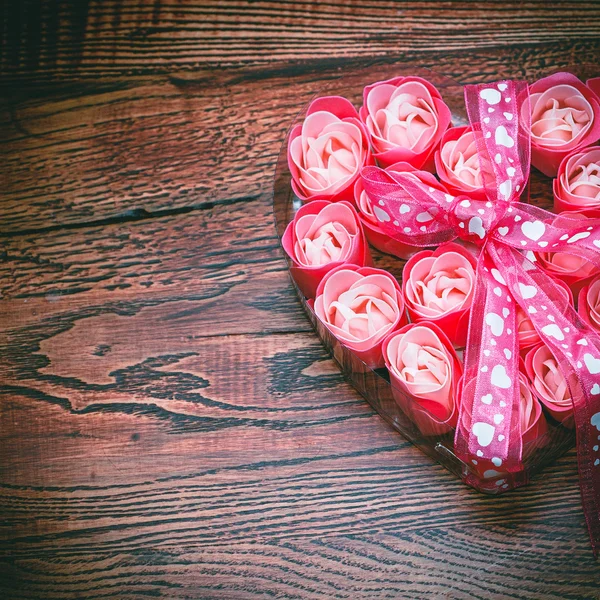 Coração com rosas e arco no fundo de madeira — Fotografia de Stock