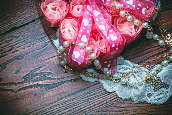 Coração com rosas e arco no fundo de madeira — Fotografia de Stock