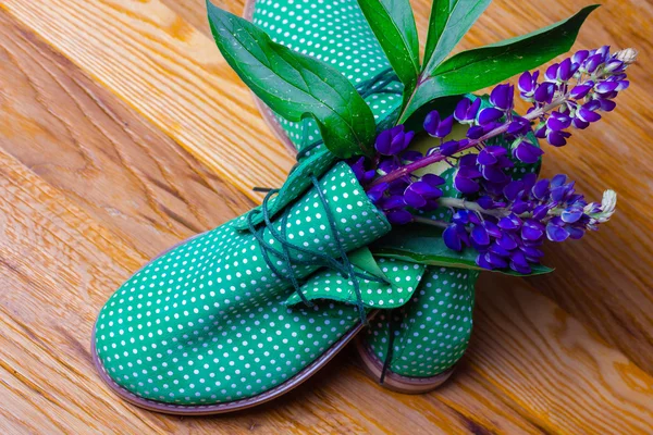 Funny green shoes with flowers in it. wood texture