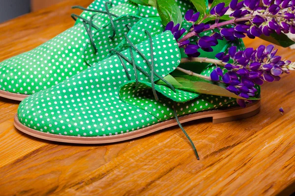 Funny green shoes with flowers in it. wood texture
