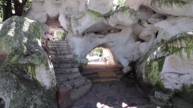 La Plata 'nın Paseo del Bosque parkındaki Grotto' nun detaylı görüntüsü. Yosun kaplı kayalar, yoğun bitki örtüsü, merdivenler ve kolay keşif için davet edici tüneller..