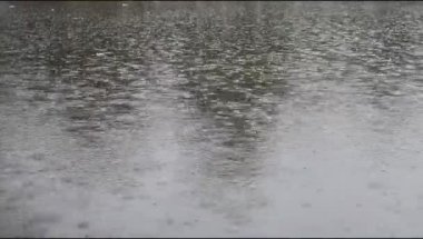 Yağmur damlaları suya düşer. Yapay bir gölün sularına düşen yağmur damlalarına yakın çekim