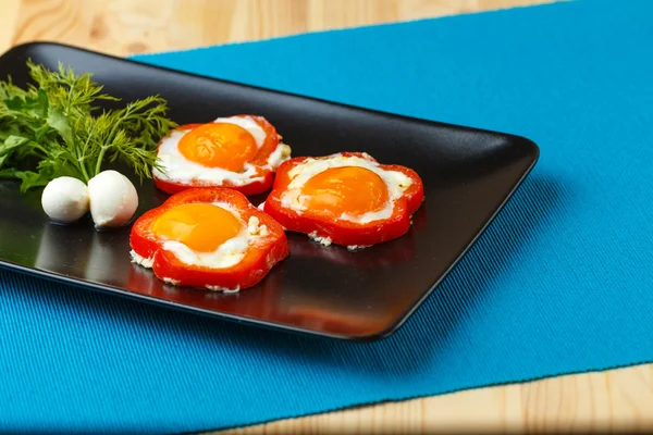 Oeufs dans des poivrons sur une assiette noire — Photo