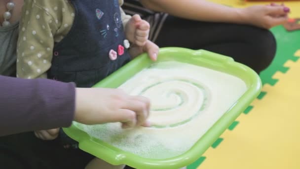 Criança desenha um dedo na bandeja com uma semolina — Vídeo de Stock