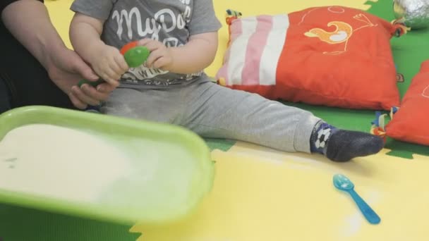 Αγόρι εφιστά με ένα κουτάλι σε ένα δίσκο με ένα σιμιγδάλι — Αρχείο Βίντεο