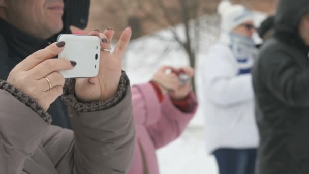 Mujer toma deportes en un teléfono blanco en invierno — Vídeo de stock