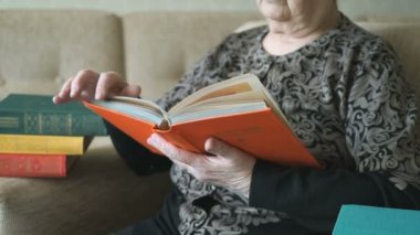 Eski büyükanne kanepede kitap okuma