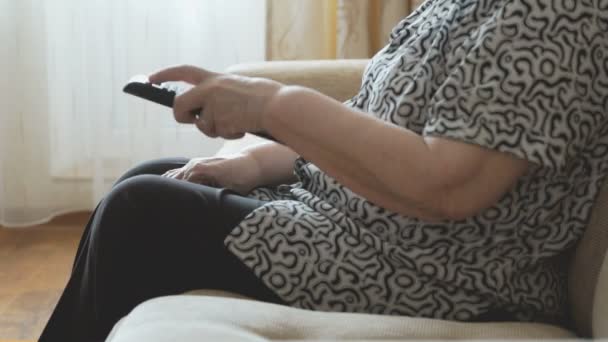 Vieja sosteniendo un mando a distancia — Vídeo de stock