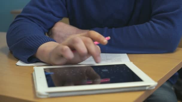 Студент, сидящий за столом, пишет в блокноте — стоковое видео
