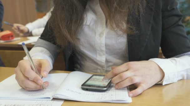 Chica sentada en el escritorio escribe texto en un cuaderno — Vídeos de Stock