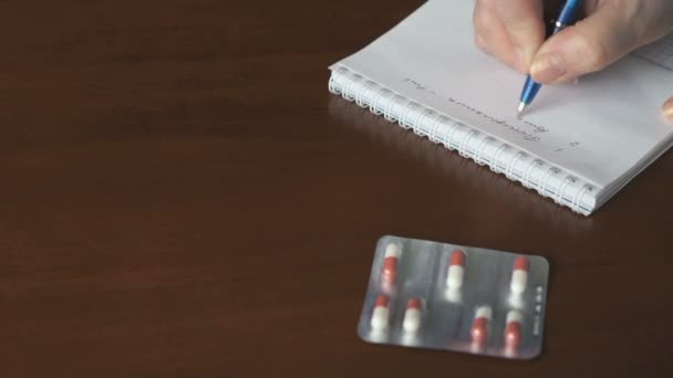 Female hand writes a note about taking tablets — Stock Video