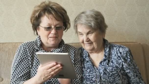 Twee bejaarde vrouwen bekijken foto's met behulp van een tablet — Stockvideo