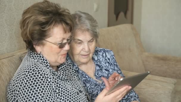 Две женщины смотрят фотографии на цифровом планшете — стоковое видео
