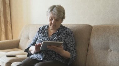 Yaşlı kadın kanepede oturan bir cep telefonu konuşurken