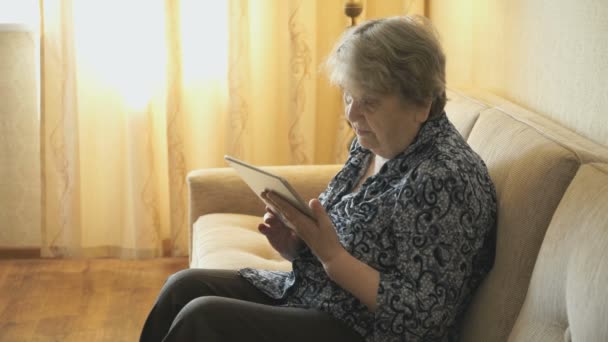 Ηλικιωμένη γυναίκα κοιτάζει εικόνες χρησιμοποιώντας μια ψηφιακή δισκίο — Αρχείο Βίντεο