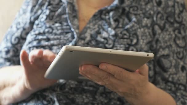 Oude vrouw kijkt naar foto's met behulp van een digitaal tablet — Stockvideo