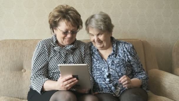 Twee vrouwen kijken naar foto's met behulp van een elektronische tablet — Stockvideo