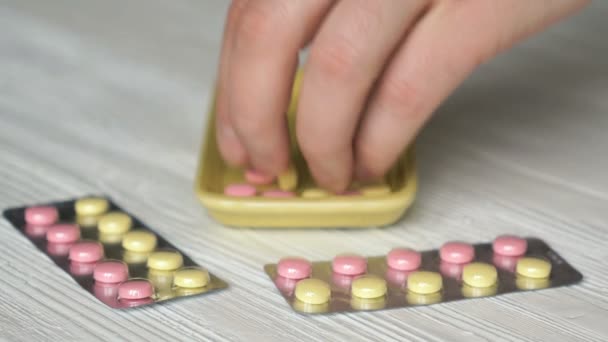 Hand sammelt die Tabletten in einem gelben Behälter — Stockvideo