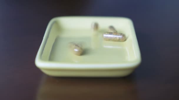 Таблетки розкидані в контейнері на столі — стокове відео