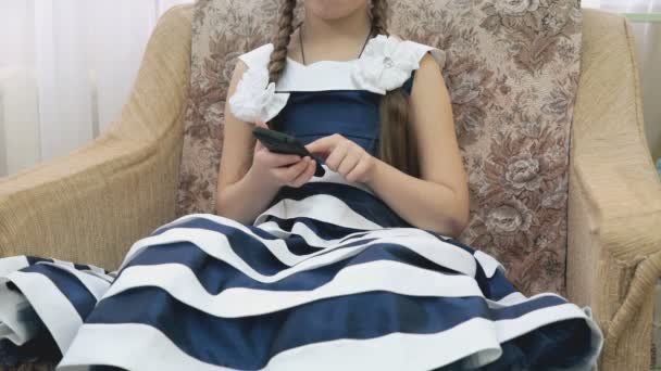 Маленькая девочка держит смартфон и играет в игру — стоковое видео