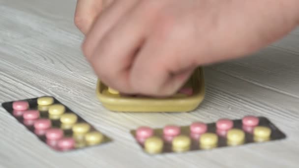Hand-verzamelt de tabletten in een gele container — Stockvideo