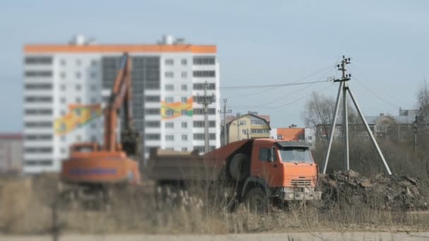 Grävmaskin uppladdningar en lera i en lastbil med hjälp av en hink — Stockvideo