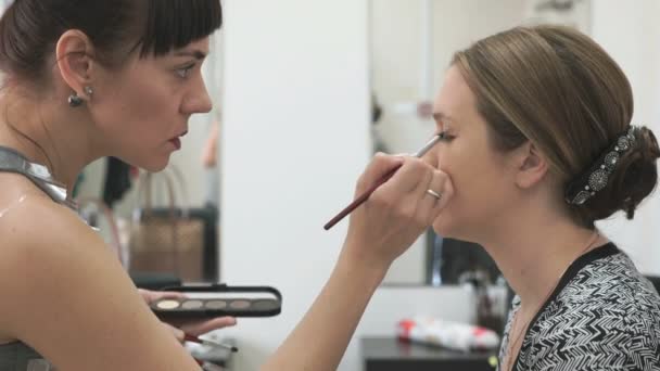 Καλλιτέχνης μακιγιάζ κάνοντας make-up για νεαρό μοντέλο — Αρχείο Βίντεο