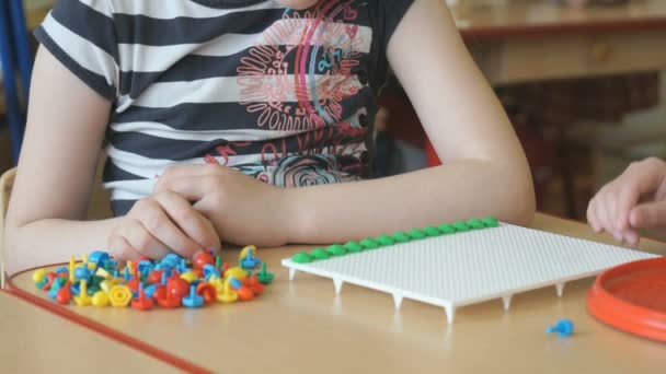 Criança pequena joga um jogo intelectual em uma mesa — Vídeo de Stock