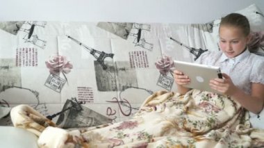 Dijital tablet ile bir yatakta yatarken genç kız