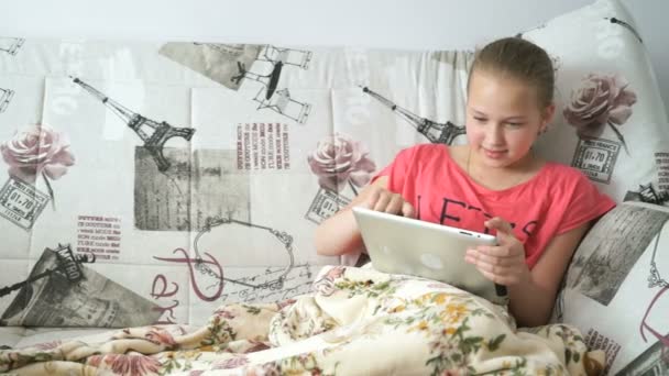 Tinédzser lány feküdt egy ágyon egy digitális tabletta — Stock videók