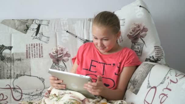 Ребенок читает цифровой планшет, лежащий на кровати — стоковое видео