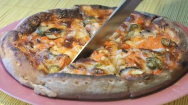 Pizzadan çelik bir bıçak kullanarak dilimler halinde keserek
