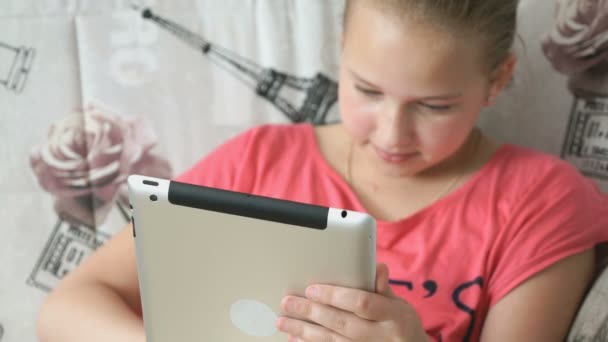 Barnet ligger på sängen med en digital tablett — Stockvideo