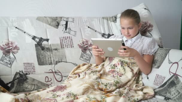 Dijital tablet ile bir yatakta yatarken genç kız — Stok video