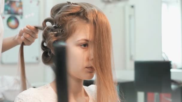 Master makes the curls to girl at the beauty salon — Stock Video