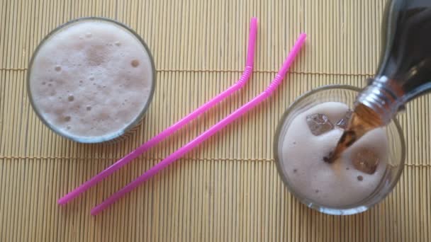 Dos vasos de cola con hielo sobre mesa de madera — Vídeos de Stock