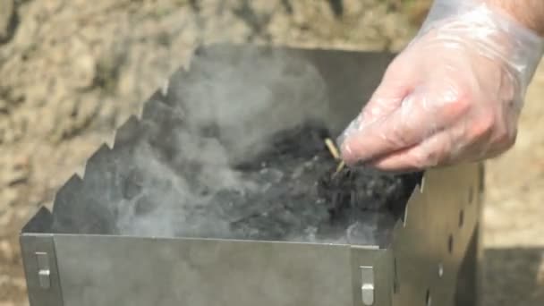 Hand with a burning match ignites the charcoal — Stock Video